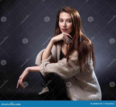 Photo Of Sitting Woman With Long Red Hair On Dark Background Stock