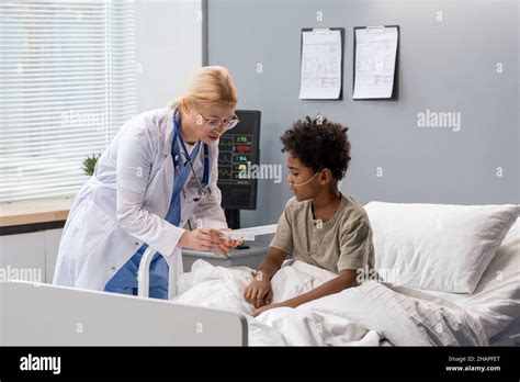 Femme mature médecin prescrivant la médecine à petit garçon et expliquant comment la prendre