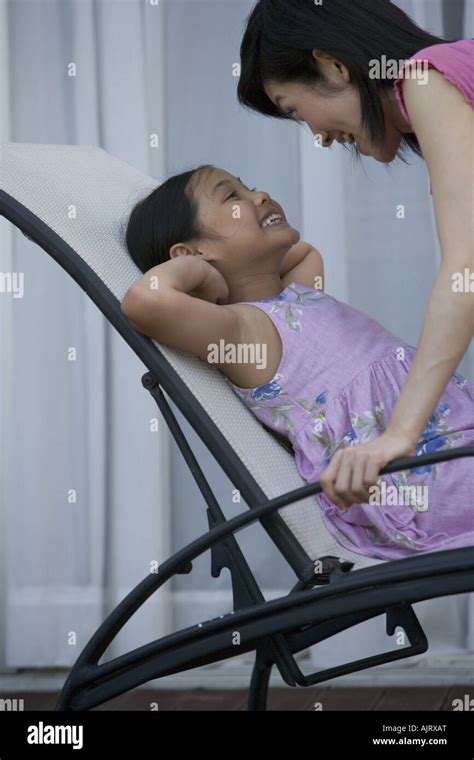 Side Profile Of A Daughter Lying On A Lounge Chair With Her Mother