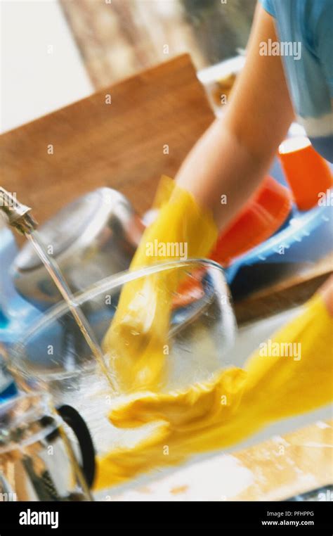 Woman Wearing Yellow Rubber Gloves Washing Glass Bowl Under Running