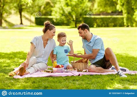 Familia Feliz Que Tiene Comida Campestre En El Parque Del Verano Imagen