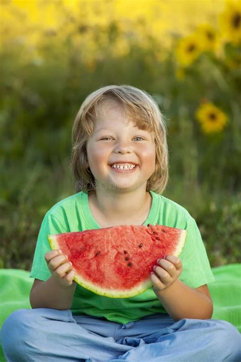 Niño Feliz Que Come La Sandía En Jardín Muchacho Con La Fruta Al Aire