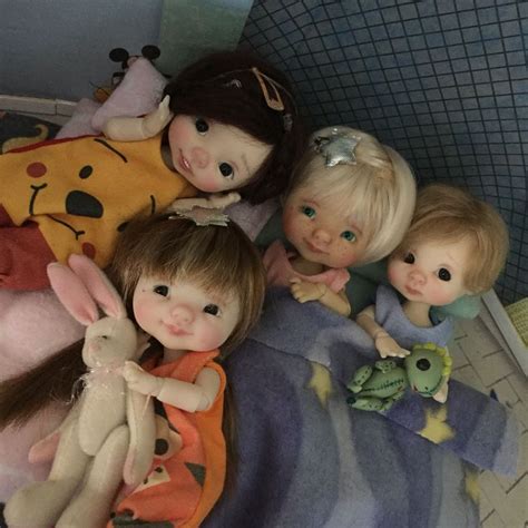 Four Dolls Laying On Top Of A Bed Next To Each Other