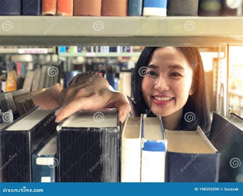 Mujer Joven Recogiendo Un Libro Del Estante En Una Biblioteca Foto De