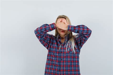 Femme blonde couvrant les yeux avec les deux mains en chemise à