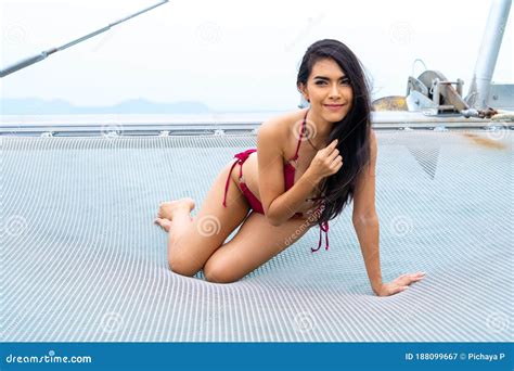 Asian Woman In Bikini Lay Down Relaxing On Cruise Yacht With Background Of Blue Water Sea