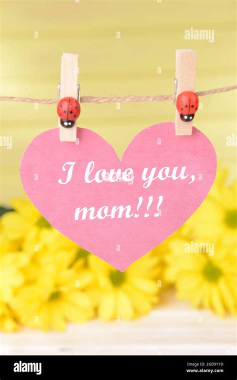 Happy Mothers Day Message Written On Paper Heart With Flowers On Yellow