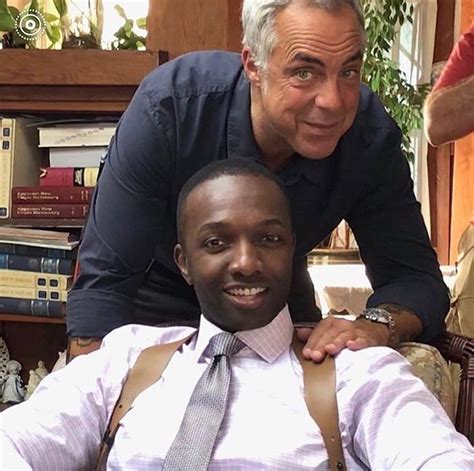 two men pose for the camera in front of bookshelves