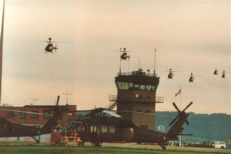 An Army Helicopter Is Parked In Front Of A Control Tower With Several