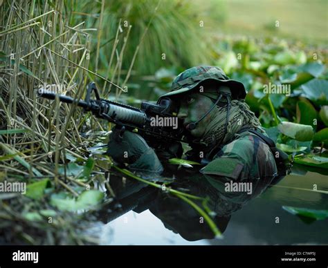 U.S. Navy SEAL crosses through a stream during combat operations Stock ...