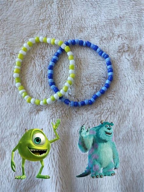 Two Bracelets With Monsters On Them Sitting On A Bed Next To Each Other