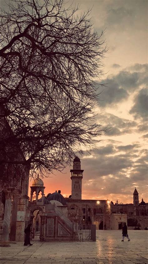 The Sun Is Setting Over An Old Building With A Clock Tower In The