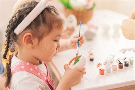 Menina Em Orelhas De Coelho Pinta Ovos Tintas Imagem De Stock