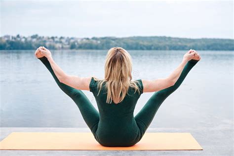 Young Blond Woman Wearing Green Overall With Bare Feet Doing Yoga Pose