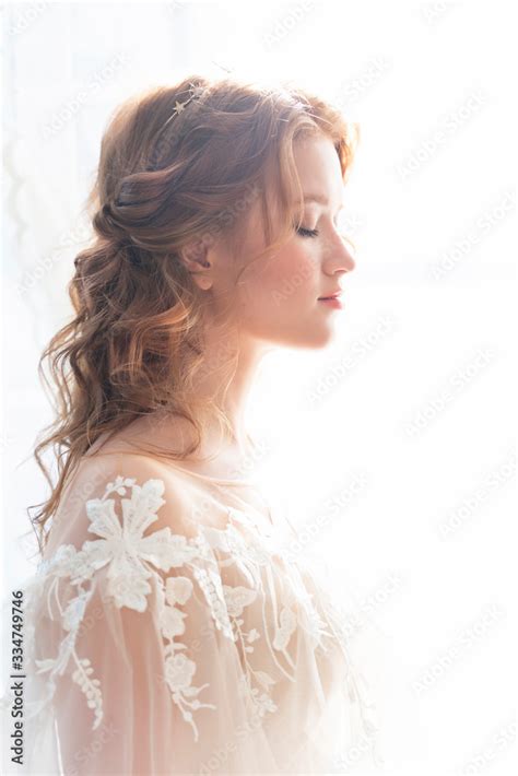 Beautiful Natural Redhead Girl Bride With Nude Makeup Wearing A White Dress Stands At The