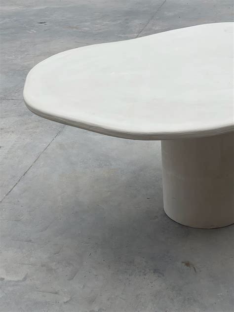 Dining table in off white concrete ciré in an organic shape The table