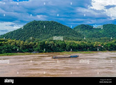 A Traditional Laos Slow Boat Glides Through The Muddy Lower Basin Of