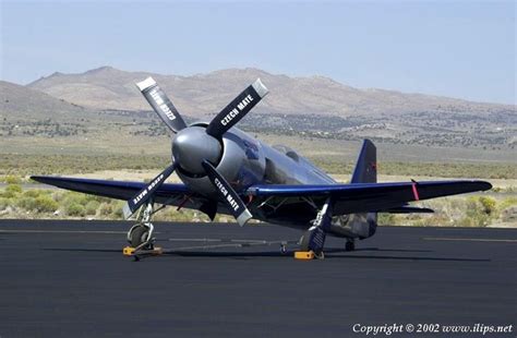 An Airplane Is Parked On The Tarmac With Mountains In The Background