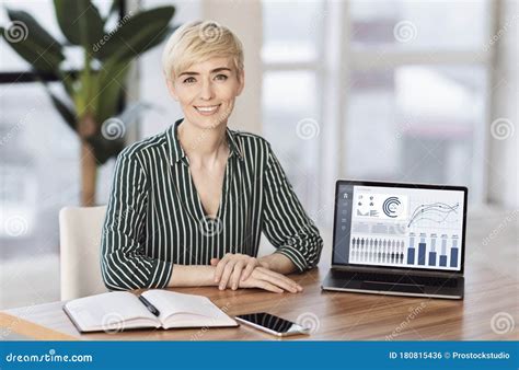 Smiling Female Manager Sitting At Desk With Laptop Stock Photo Image