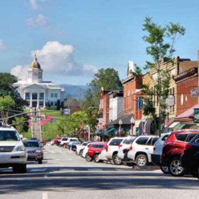 Cars Are Parked On The Street In Front Of Buildings And A White