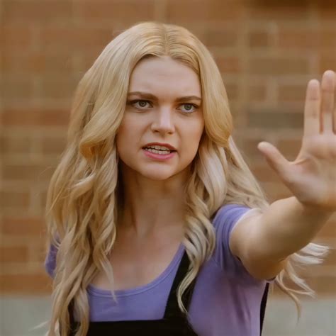 A Woman With Long Blonde Hair And Blue Eyes Holding Her Hand Up In The Air