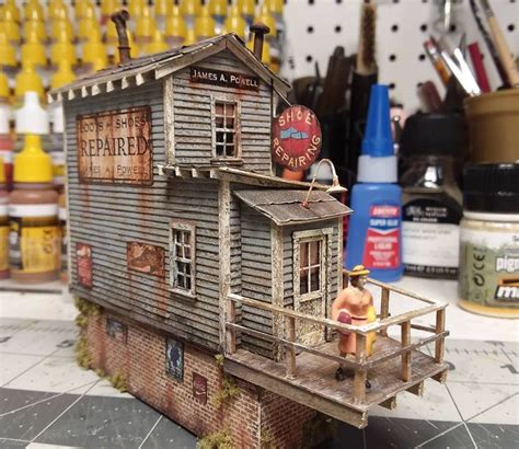 a doll house made out of an old wooden building with a man standing on the porch