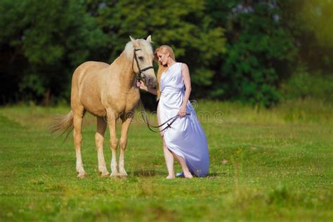 Blonde De Femme De Cavalier Avec De Longs Cheveux Dans Une Robe Blanche Avec Un Train Posant Sur