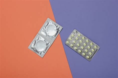 Premium Photo Condoms In Packaging Birth Control Pills On A Colored