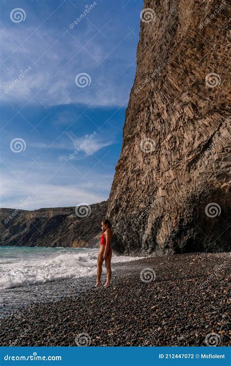 A Beautiful And Brunette In A Red Swimsuit On A Pebble Beach Running