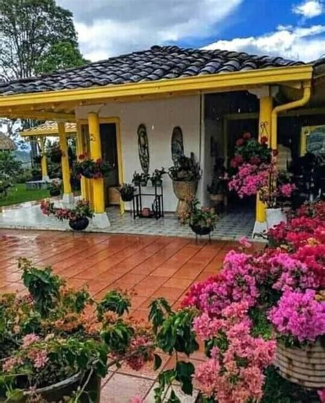 A House With Flowers In The Front Yard And On The Back Porch Potted Plants