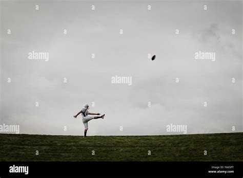 A Football Player In Uniform Side View Practicing His Kicking Ball