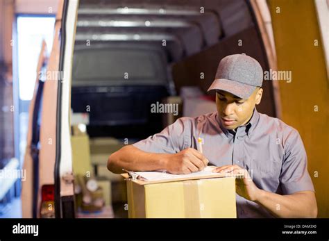 Delivery Boy Writing On Clipboard In Van Stock Photo Alamy