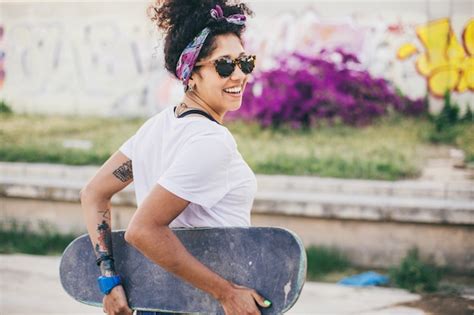 Brunette Mädchen posiert mit Skateboard Kostenlose Foto