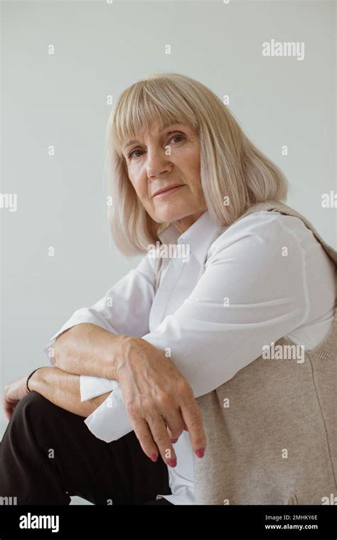 Studio Portrait Of Gray Haired Senior Woman Leaning On Elbows Looking