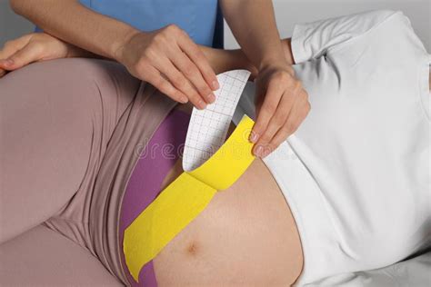 Pregnant Woman Visiting Physiotherapist Doctor Applying Kinesio Tape