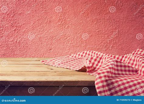 Empty Wooden Deck Table With Red Checked Tablecloth Over Red Wall Stock