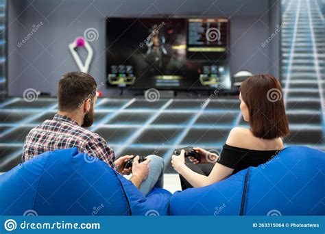 Young Couple Playing Video Games, Sitting on Chairs in a Gaming Club ...