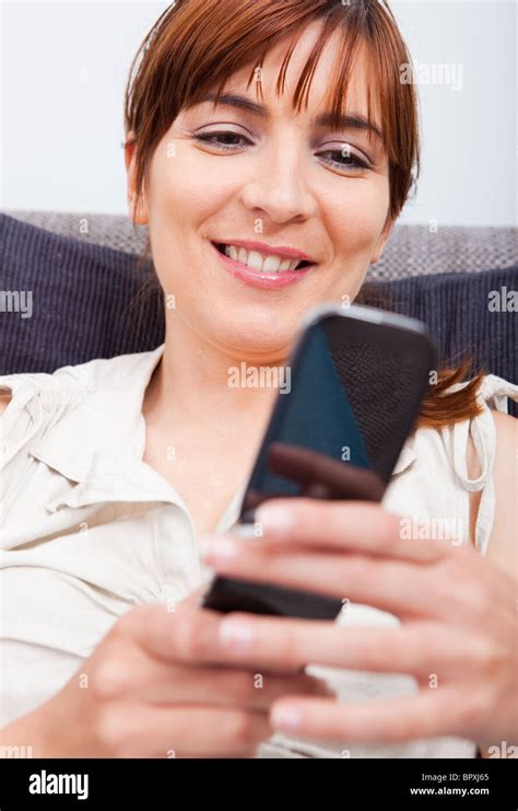 Portrait Of A Beautiful Woman Seated On Sofa Holding A Cellphone And