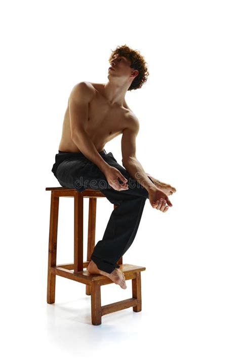 Shirtless Muscled Man With Naked Torso Posing Sitting On Stool Against