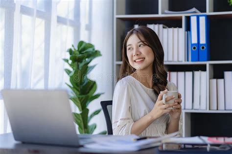 Pretty Smiling Asian Female Accountant Working On Laptop Computer In