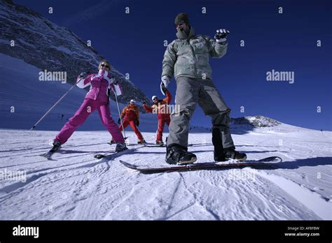 Two People Having Ski And Snowboard Lessons With Ski Instructors