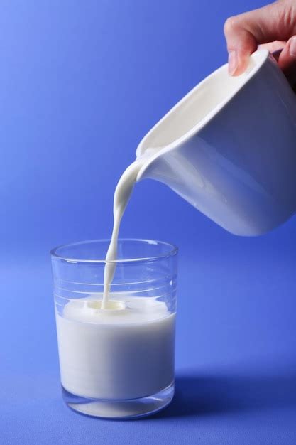 Premium Photo Pours Milk In Glass On Blue Background