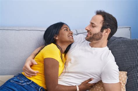 Man And Woman Interracial Couple Hugging Each Other Lying On Sofa At