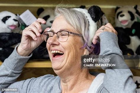 A Woman Laughs As She Tries On Panda Ears While Visiting The Giant