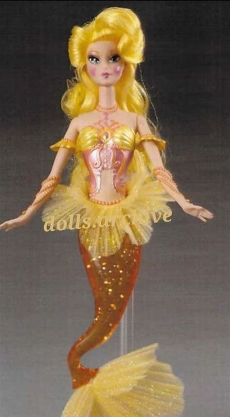 The Doll Is Wearing A Yellow Dress And Gold Headpiece With Sequins On It