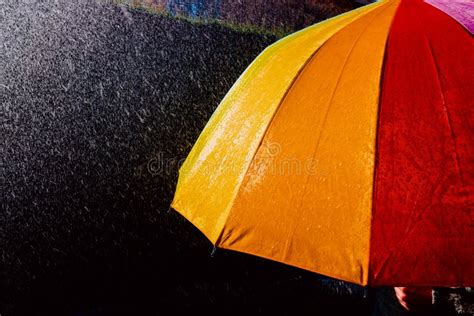 Rain Falls On An Umbrella Among Sun Rays Dark Background In Black