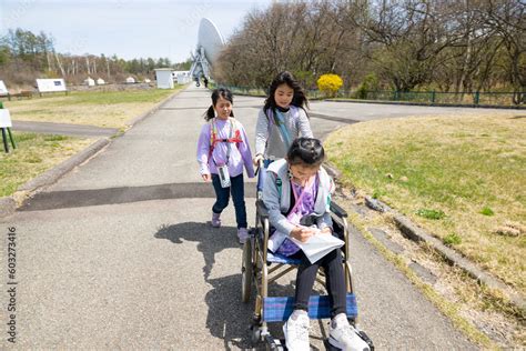 車いすに乗った女の子と学校の遠足に行く小学生の友達 Foto De Stock Adobe Stock