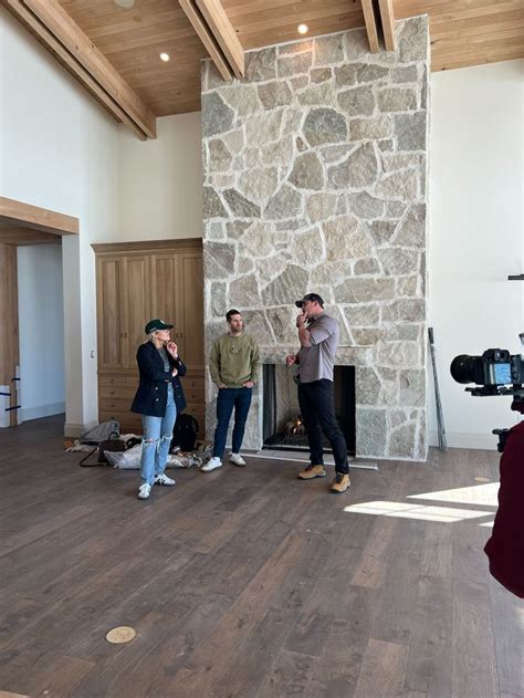 Three Men Standing In Front Of A Stone Fireplace With Cameras Around