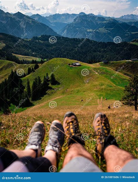Hikers Showing Their Shoes while Overlooking Mountain Ranges in the