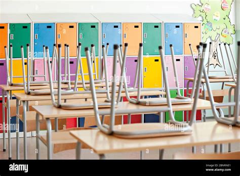 Modern empty classroom with colorful lockers and raised chairs on the tables - back to school ...